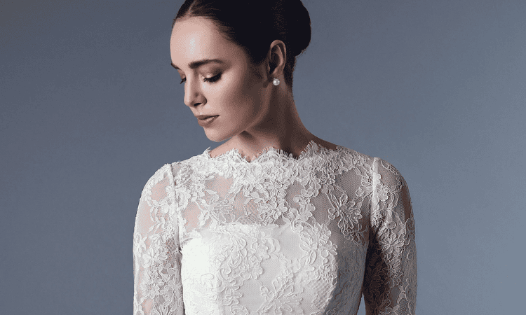 Bride wearing a long-sleeve lace wedding dress with a high neckline and intricate floral detailing.