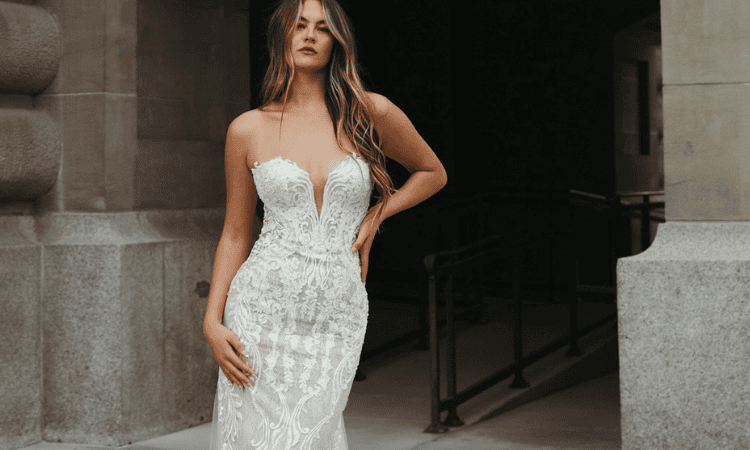 Bride wearing a strapless white lace wedding dress with a plunging neckline, fitted silhouette, and intricate floral detailing.